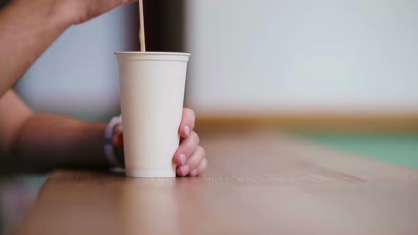 Closeup of Male Hands Stir the Sugar in a Glass with Coffeee in Cafe.