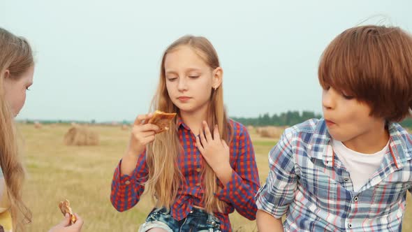 Cute Boy and Girls Eating Pizza Together in Field