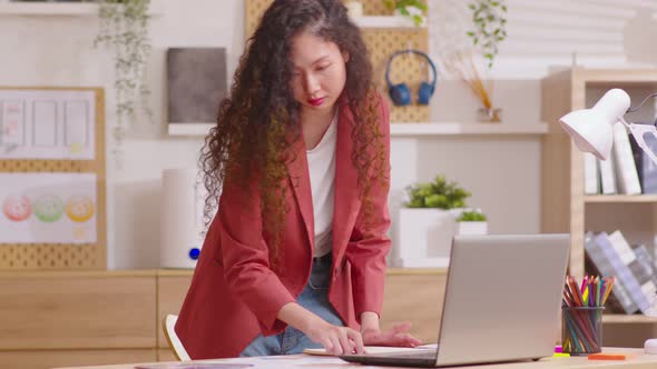 Young entrepreneur working standing at desk at home office arranging papers