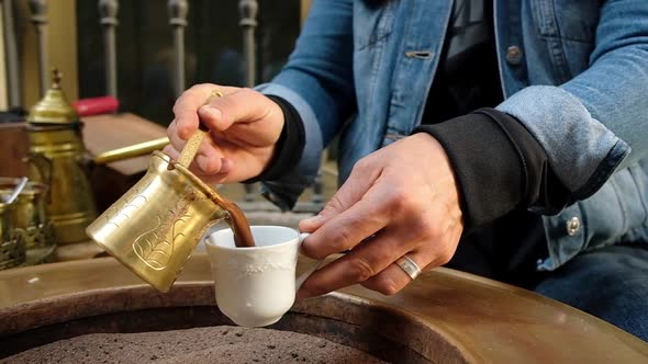 Woman's Hands Pouring Traditional Turkish Coffee in a Cup.