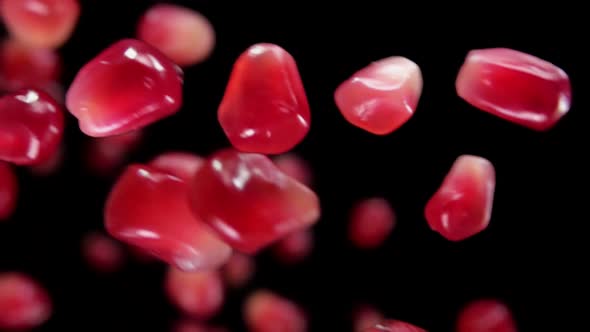 Super Closeup of Juicy Pomegranate Grains Falling Down on the Black Background