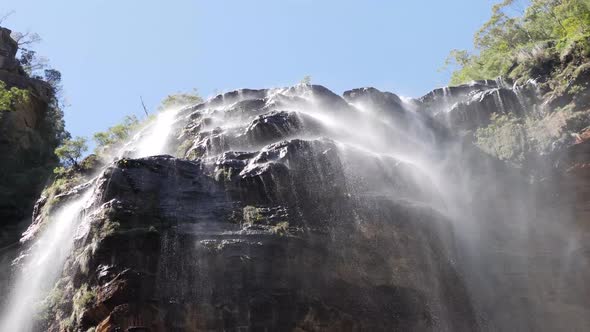 Low angle view on wentworths falls in the blue mountains, australia with blue sky and shallow water