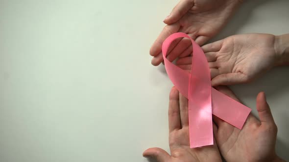 People Hands Showing Pink Ribbon to Camera, Breast Cancer Prevention Campaign