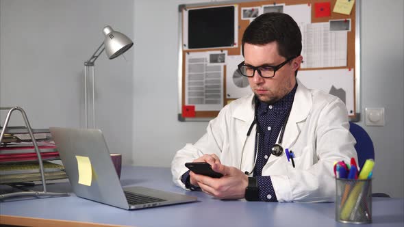 A Young Doctor Examines X-rays Pictures on a Mobile Phone in the Private Clinic