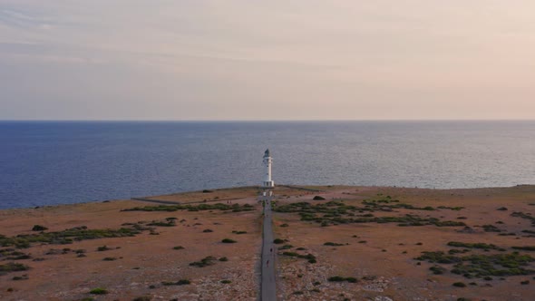 Lighthouse cupola dolly in, empty road in dry plain and calm blue sea