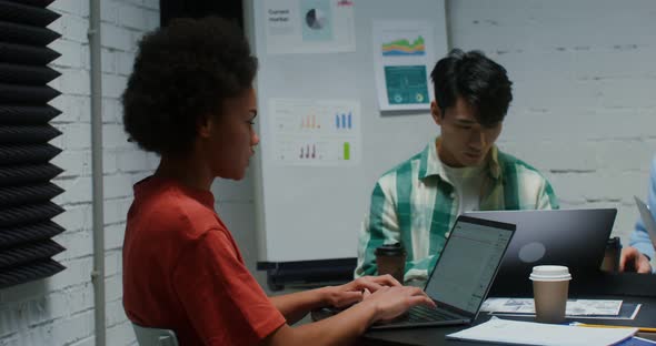 Young Colleagues Work in Team Using Laptop and Communicating Sitting in Office