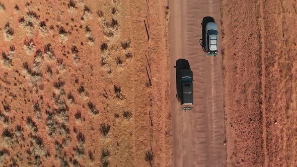 Aerial Top Down of Black Truck Overtaking Silver Station Wagon on Dirt Road