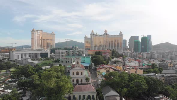 Rising drone reveal shot of Taipa skyline in Macau with park and church in foreground and casino hot