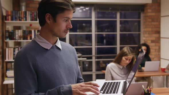 Creative businessman with laptop smiling in modern office