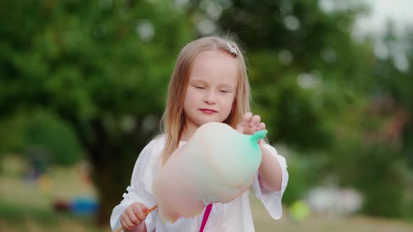 Little girl eating candyfloss in the park