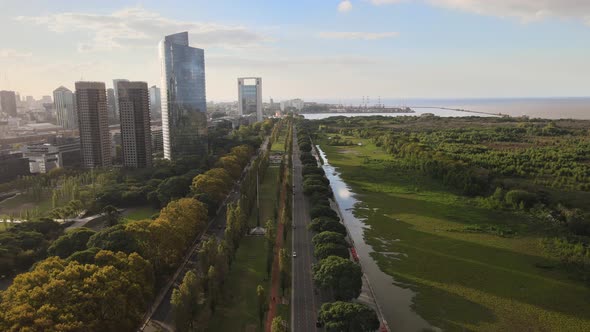 Aerial along street between skyscrapers and greenlands in Buenos Aires