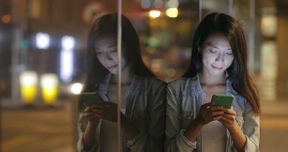 Woman using cellphone at night in Hong Kong 