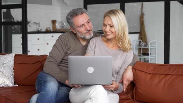 Middleaged Couple in Love Using Laptop Sitting on the Couch at Home