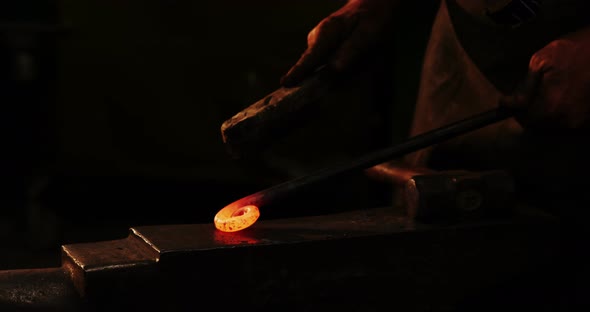 Mid-section of blacksmith using wire brush on hot iron