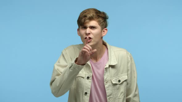 Slow Motion of Young Angry Guy Shushing at Camera Hushing and Pressing Finger to Lips Pointing at