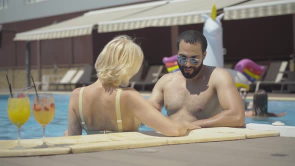 Handsome Young Middle Eastern Man in Sunglasses Flirting with Gorgeous Blond Caucasian Woman in