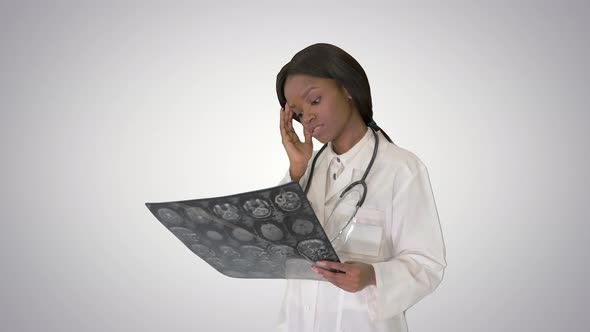 Young Female Doctor Standing Looking at X-ray of a Brain on Gradient Background.