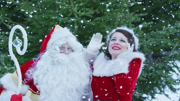 Santa Claus and Christmas girl enjoying the snowfall alt