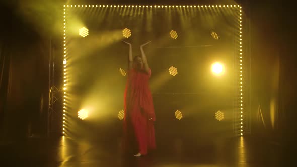 A Young Girl Dancer in a Red Sari. Indian Folk Dance. Shot in a Dark Studio with Smoke and Yellow