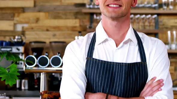 Portrait of male waiter standing with arms crossed