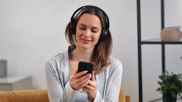 Joyful Female Listening Music in Wireless Headphones Use Mobile App