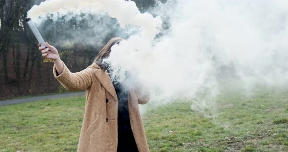 Woman Makes Emergency Flare Signal with White Smoke. Hipster Pretty Girl with Smoke Bomb