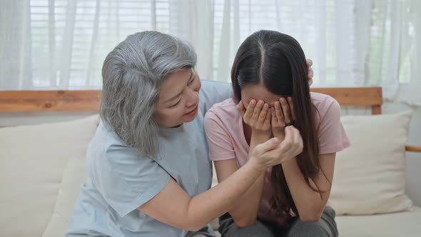 Asian senior mother consoling and comforting upset depressed young girl daughter crying for problem.