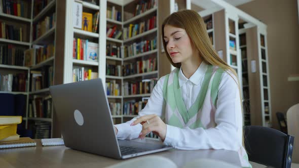 Woman Browsing Internet on Laptop in Library