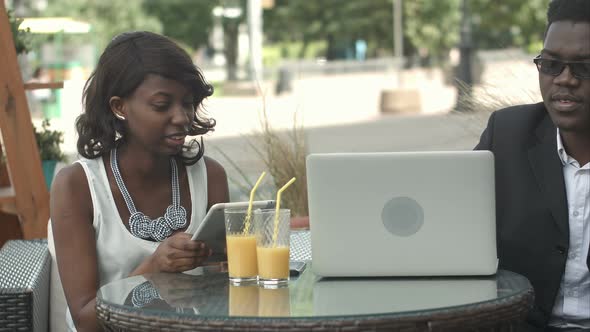 Afro-american Business Man and Woman Working Together in Modern Cafe, Having Phone Calls, Using