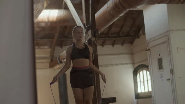 Medium Shot of Beautiful Woman Jumping Rope Alone in Gym