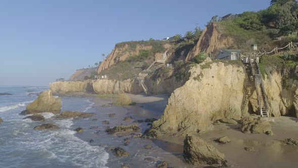 Aerial shots of El Matador beach over breaking waves and rocks on a hazy summer morning in Malibu, C