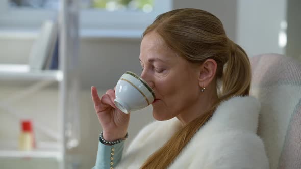 Confident Gorgeous Elegant Lady Drinking Afternoon Tea Sitting at Home Indoors