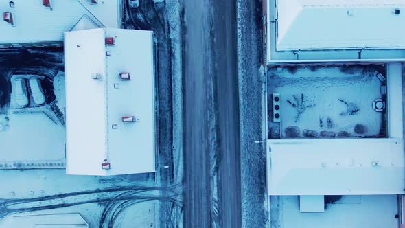 Above 90 degree angled drone shot of snowy buildings, streets and cars