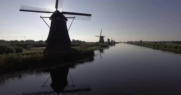 A drone shot panning forward, around Dutch Windmills during sunrise
