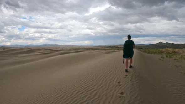 Following woman walking on sand dunes at Little Sahara in Utah