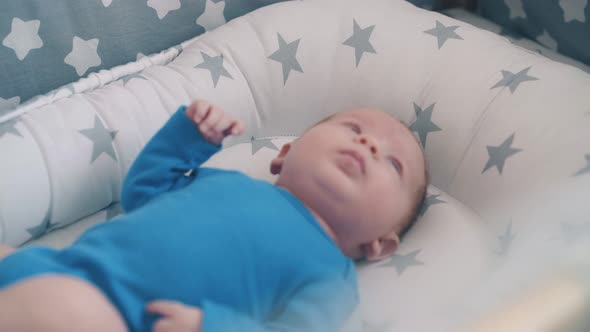 Cute Newborn Kid and Mommy Shaking Rattle Over Crib Closeup