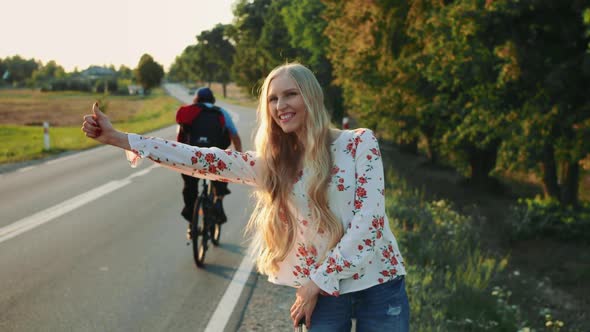 Young Lady Hitchhiking on Countryside Road.