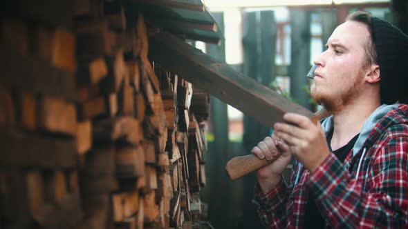 Young Man Woodcutter Putting Logs on the Stand with Other Logs