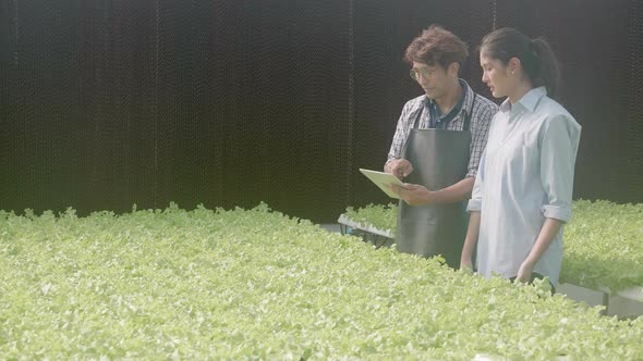 Young asian man walking and holding tablet computer talking for recommend vegetables with customer.