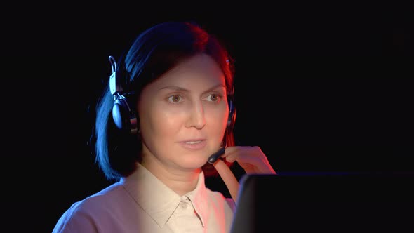 Girl in Headphones with a Headset Communicates on the Internet Via a Computer