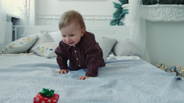 Slow Motion a Little Boy Crawls on the Bed for a Gift and Tries To Eat It