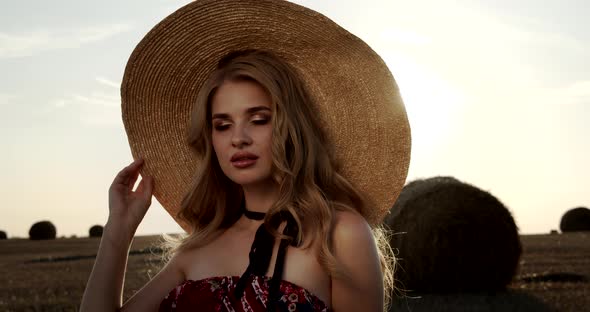 Seductive Girl Touches A Straw Hat At Sunset