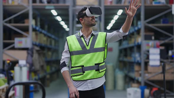 Young Middle Eastern Man in Uniform and VR Headset Looking Around Standing in Warehouse Indoors