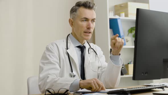 Caucasian male doctor using laptop for online meeting with patient