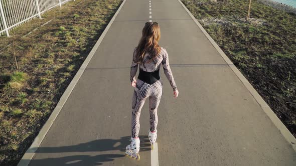 Athletic slender girl rollerblading on the path along the lake. Slow motion. Top view