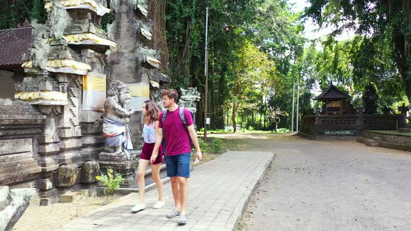 Young couple touring alongside stone walls of ancient Buddhist temple, watching beautiful sculptures