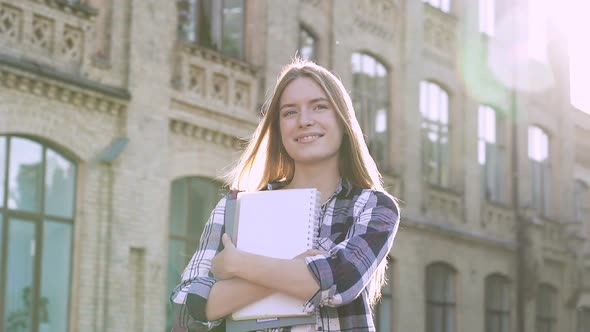 Happy Student Girl Standing Near the College. Holding Textbooks, Smiling