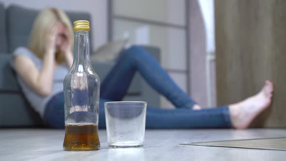 A young woman sleeps after drinking at home on the floor. Female alcoholism
