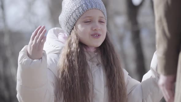 Close-up Portrait of Mischievous Little Girl Gesturing and Rubbing Eyes Outdoors. Disobedient