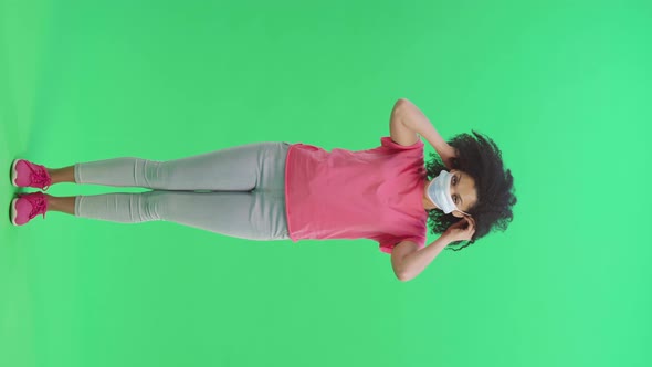 Portrait of Young Female African American Looking at the Camera and Puts on Medical Mask